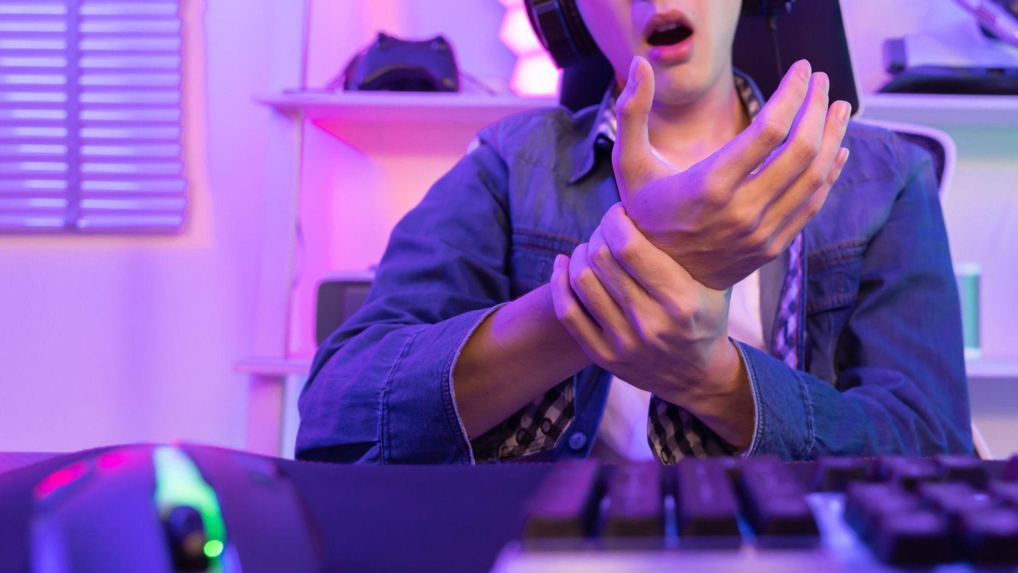 Why does my wrist hurt after gaming: a close-up of an esports player rubbing a painful wrist during a PC session.