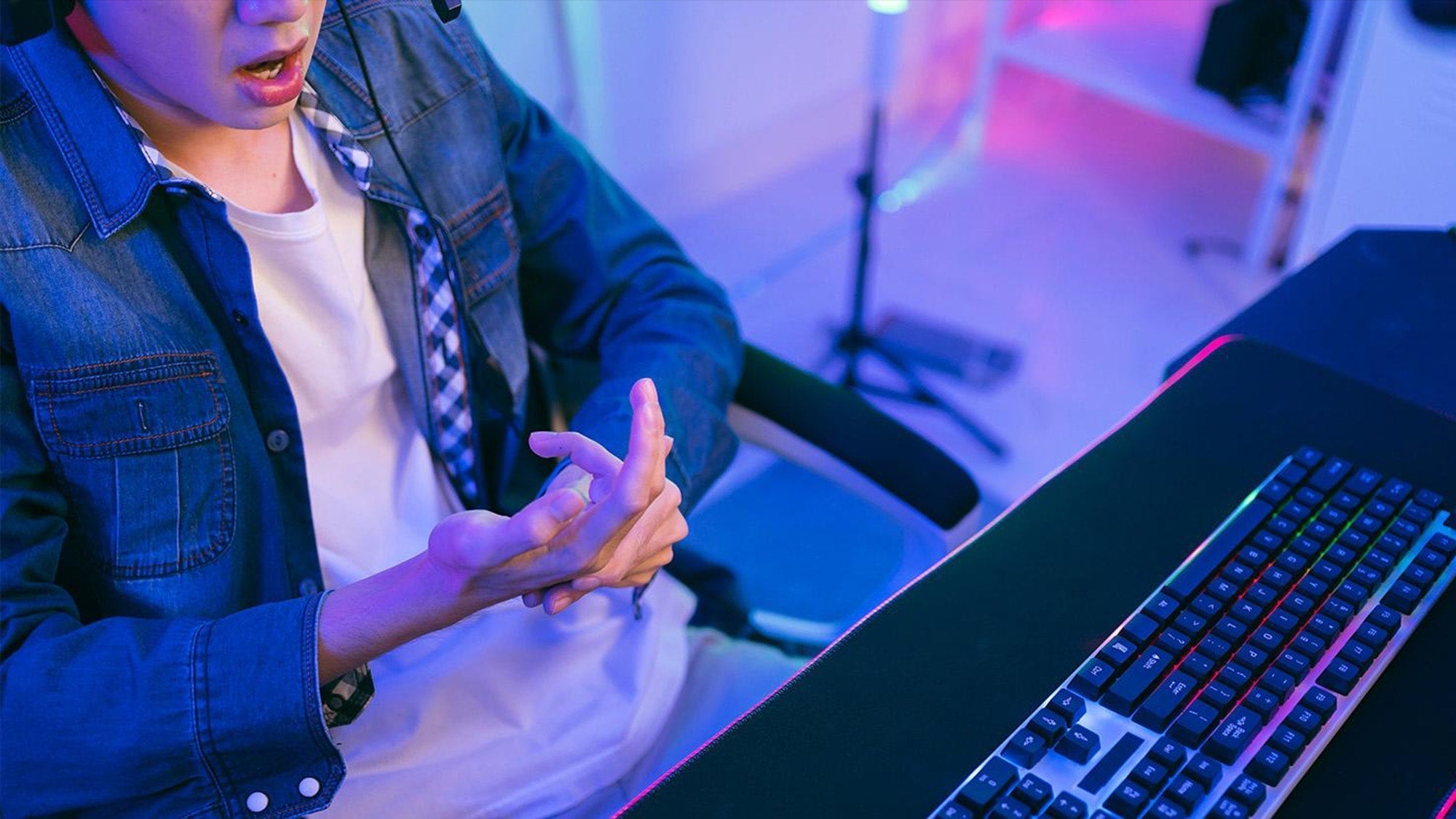 How to prevent wrist pain while gaming: a player massaging a sore hand to relieve tension during PC setup sessions.