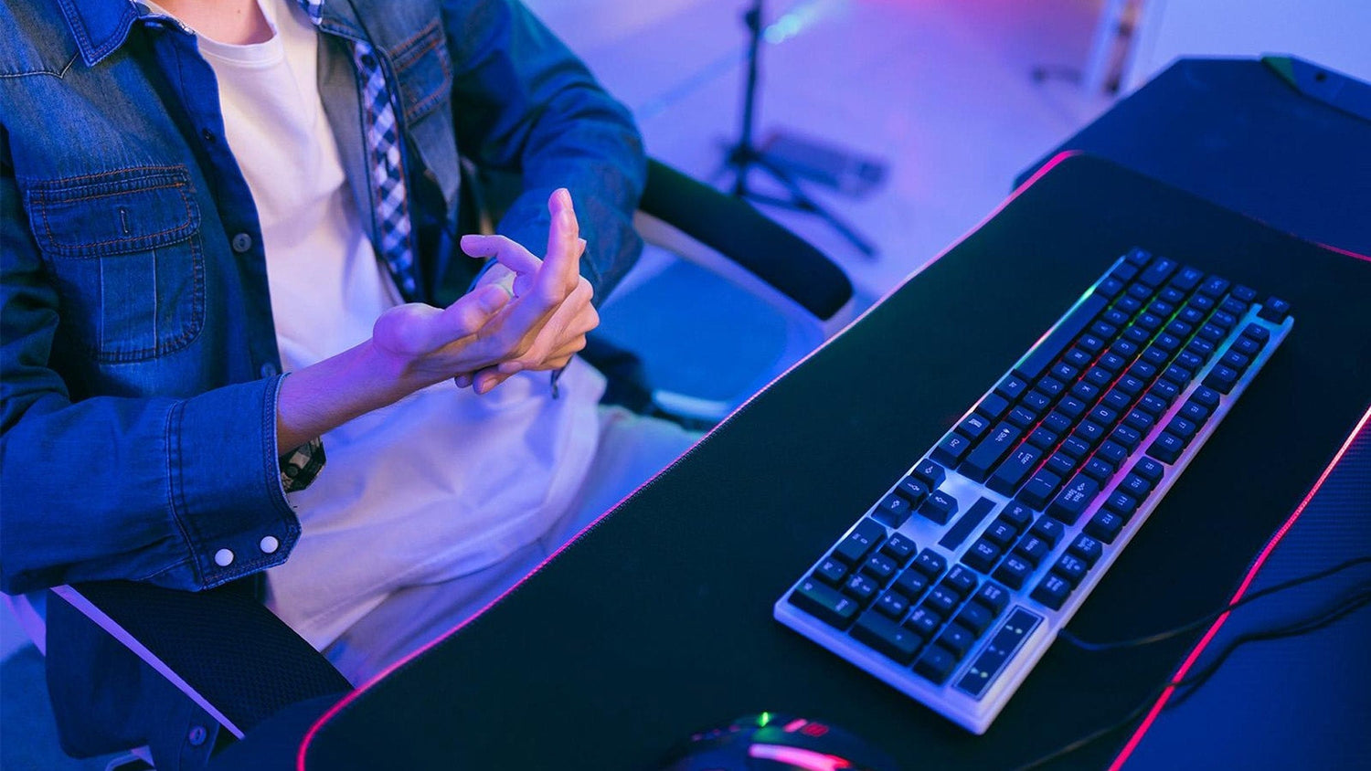 Carpal tunnel syndrome and gaming: a player massaging a painful hand in front of a computer monitor setup.