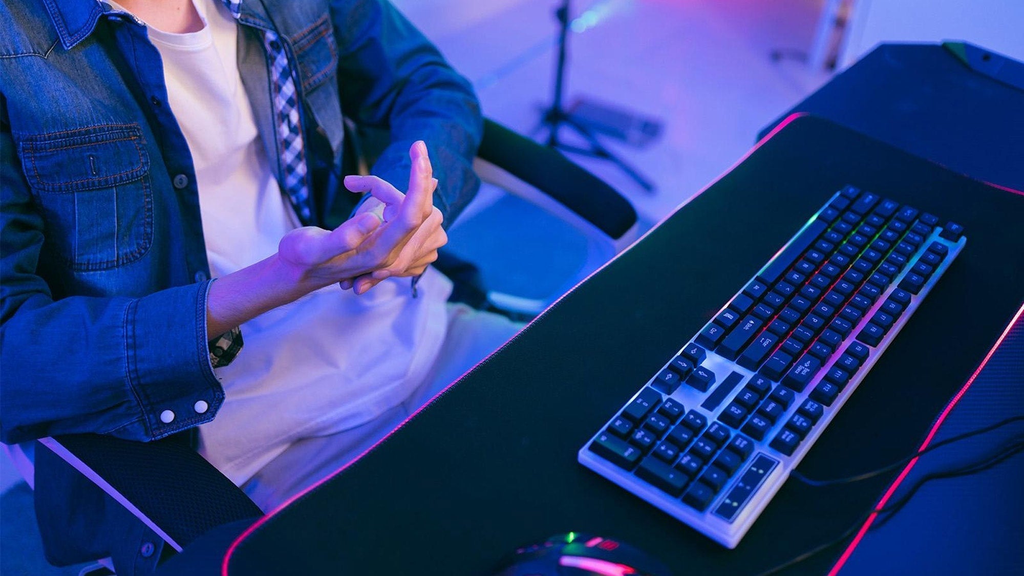Carpal tunnel syndrome and gaming: a player massaging a painful hand in front of a computer monitor setup.