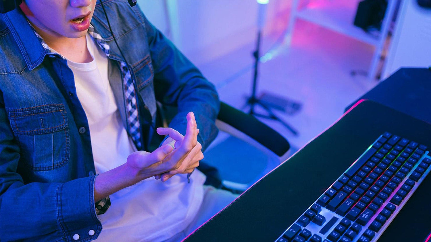 How to prevent wrist pain while gaming: a player massaging a sore hand to relieve tension during PC setup sessions.