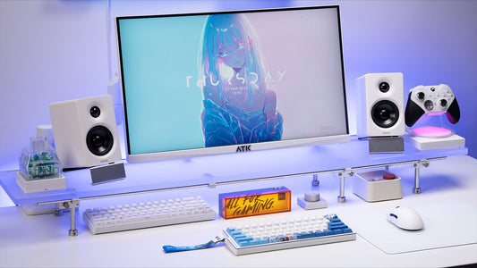 Workspace setup featuring ATK mechanical keyboards, ergonomic mouse, monitor stand, speakers, and gaming accessories on a clean white desk.