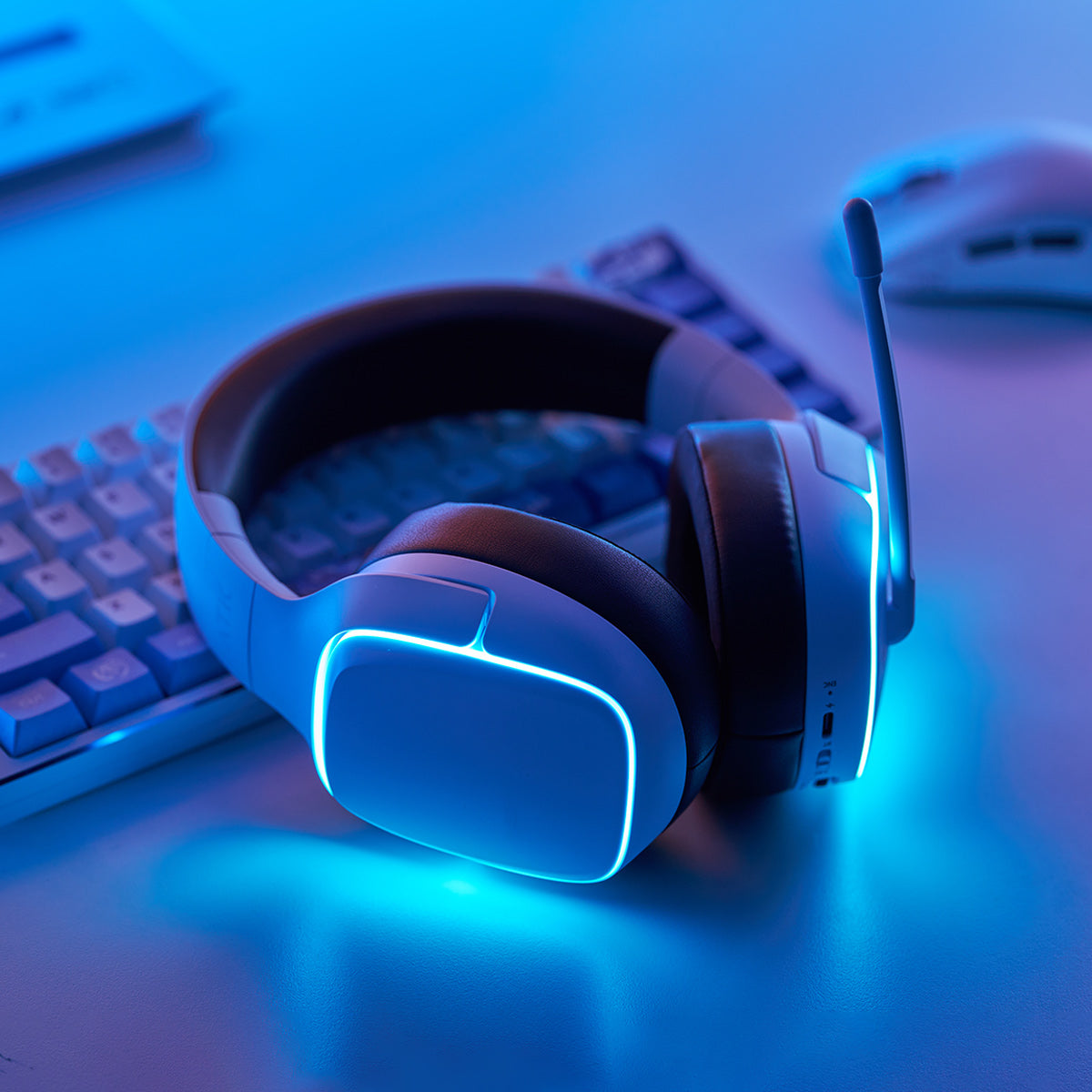White gaming headset with blue LED lights on a mechanical keyboard