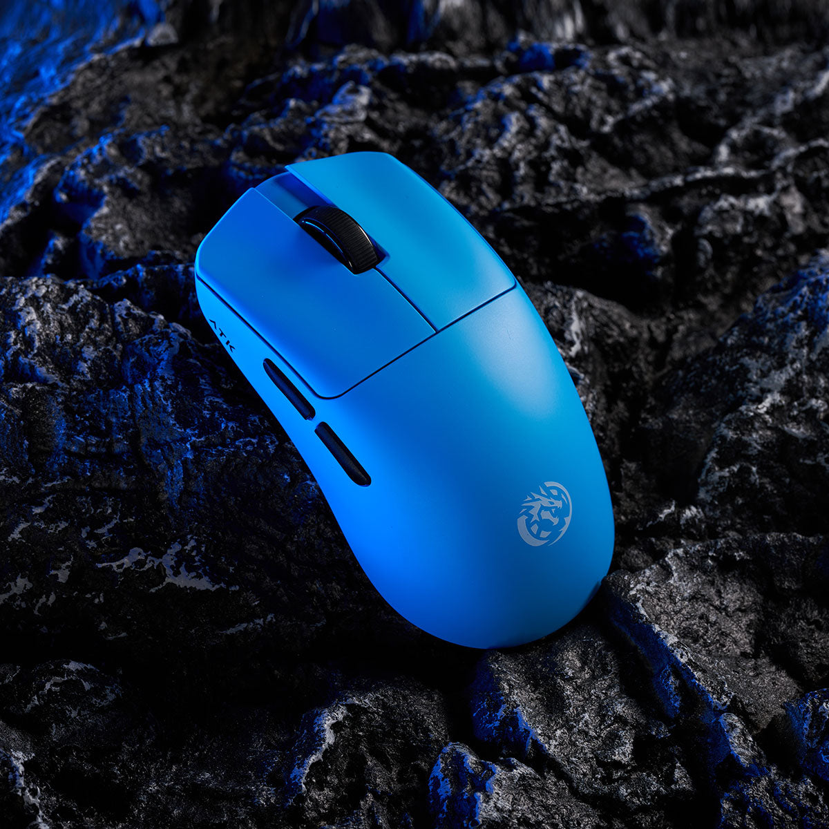 ATK Blazing Sky F1 wireless gaming mouse in vibrant blue with LEVIATAN logo, placed on dark, textured rock.