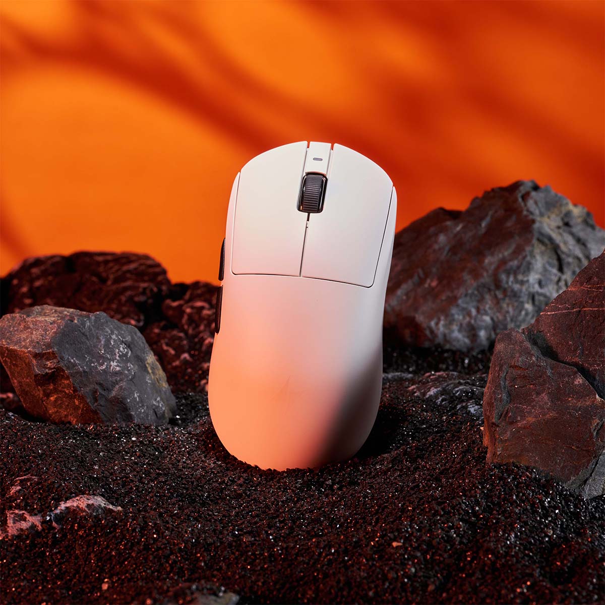 White ergonomic gaming mouse with a textured scroll wheel, set against a dramatic orange background and dark rocks.